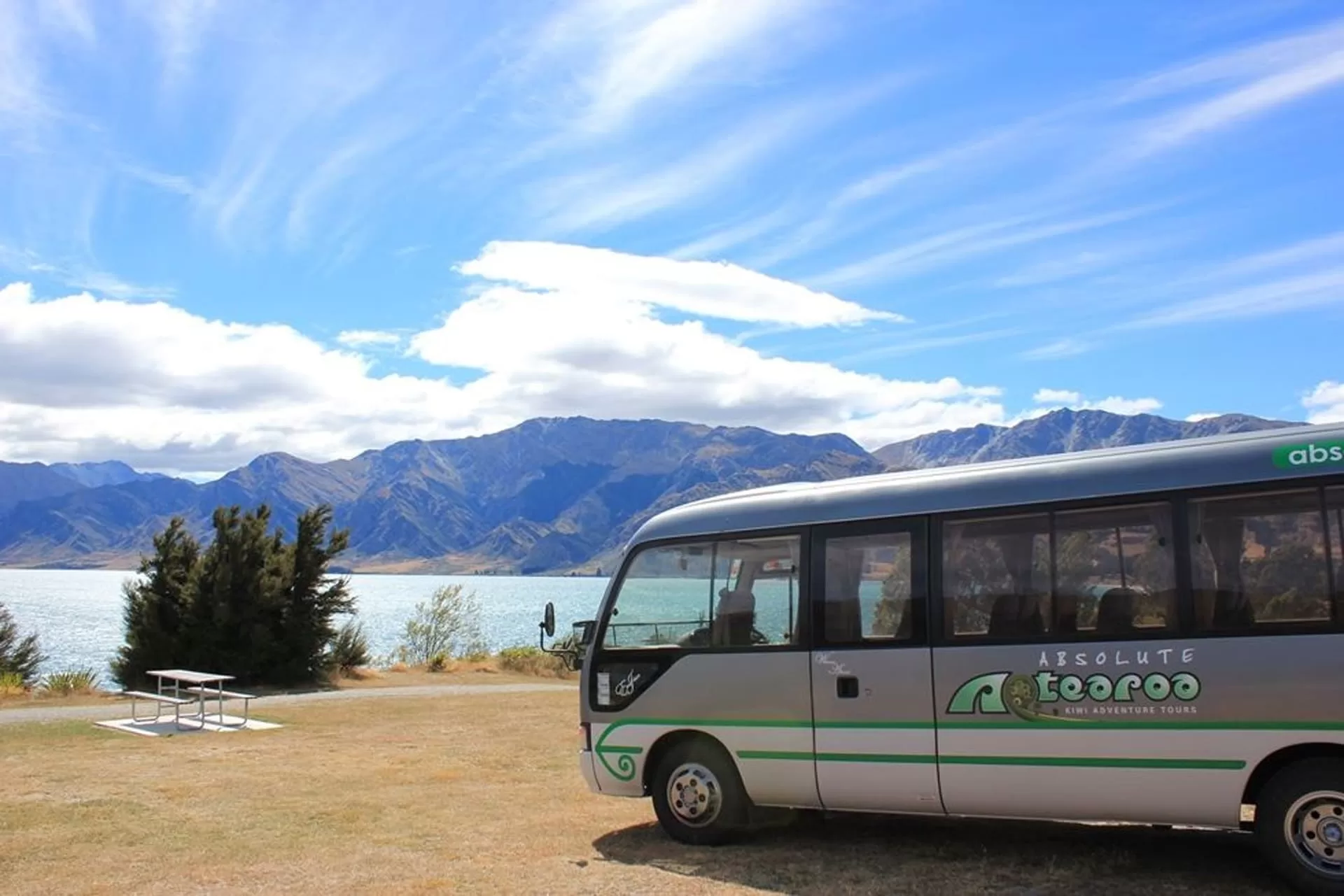 absolute tour bus in front of mountains and water
